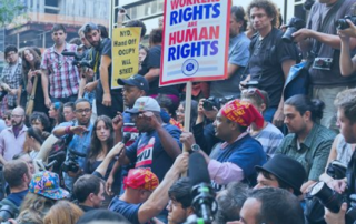 Labor organizers in a crowd with signs. one in red and blue text reads, "Workers Rights are Human Rights."