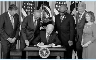 Biden signing bill into law surrounded by government officials