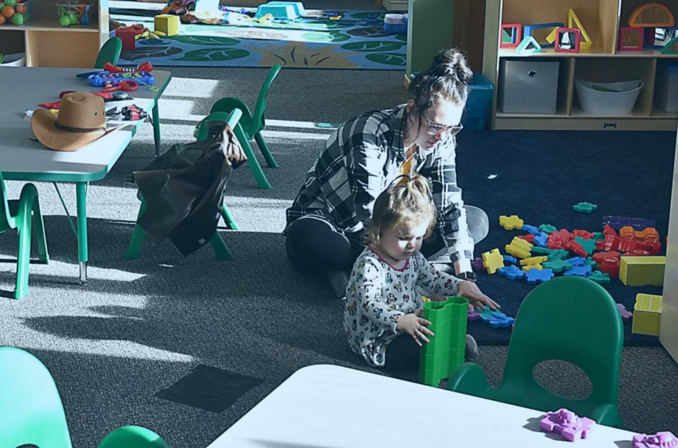 Adult and Child play on the floor in a child care setting